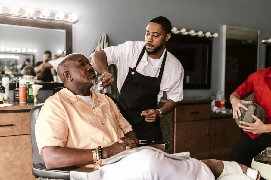 Barbeiro atendendo cliente em uma barbearia organizada